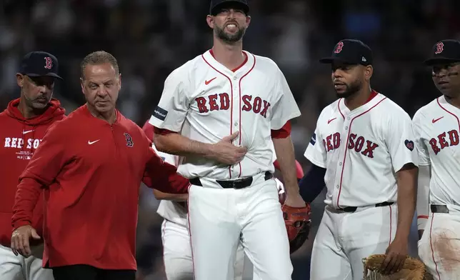 Boston Red Sox pitcher Chris Martin, center, is escorted to the dugout after fielding a line drive off the bat of Tampa Bay Rays' Josh Lowe for the final out of the top of the eighth inning during a baseball game at Fenway Park, Tuesday, May 14, 2024, in Boston. (AP Photo/Charles Krupa)