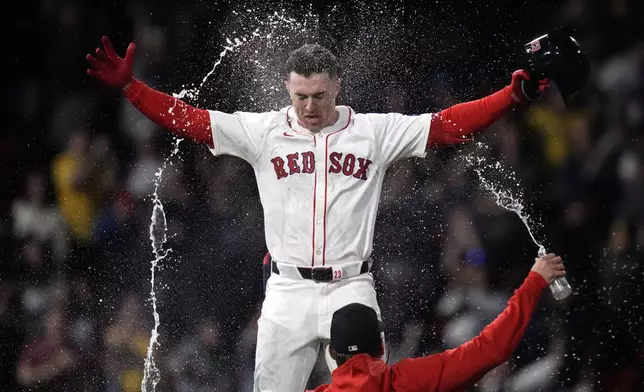 Boston Red Sox's Romy Gonzalez is doused with water after his game-winning RBI single in the 12th inning of a baseball game against the Tampa Bay Rays at Fenway Park, Tuesday, May 14, 2024, in Boston. The Red Sox won 5-4. (AP Photo/Charles Krupa)
