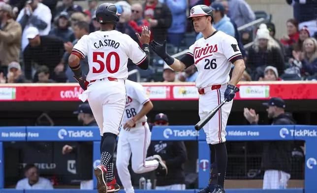 Minnesota Twins' Willi Castro, left, celebrates with Max Kepler, right, after scoring on a sacrifice fly hit by Carlos Correa during the sixth inning of a baseball game against the Boston Red Sox, Saturday, May 4, 2024, in Minneapolis. (AP Photo/Matt Krohn)