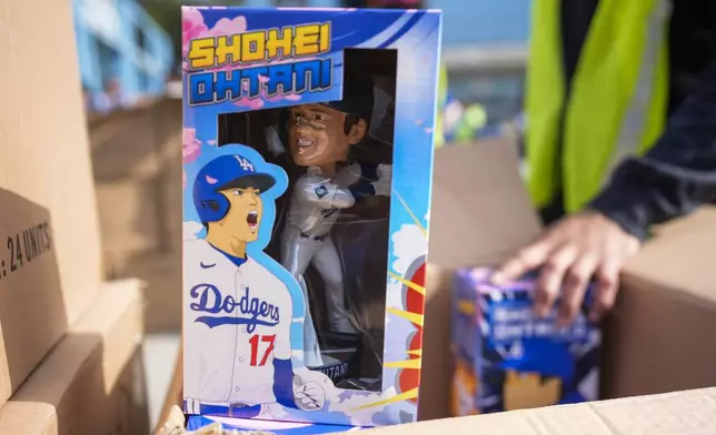 Bobbleheads of Los Angeles Dodgers designated hitter Shohei Ohtani are given to fans before a baseball game against the Cincinnati Reds in Los Angeles, Thursday, May 16, 2024. (AP Photo/Ashley Landis)