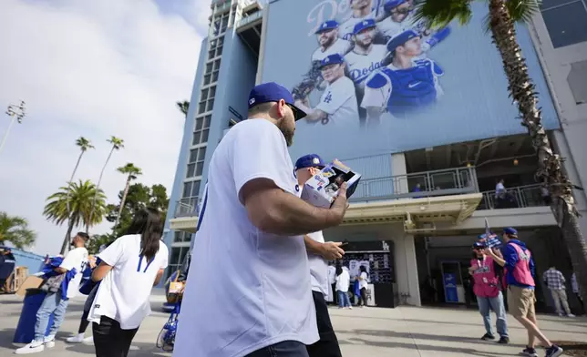 Fans carry bobbleheads of Los Angeles Dodgers designated hitter Shohei Ohtani before a baseball game against the Cincinnati Reds in Los Angeles, Thursday, May 16, 2024. (AP Photo/Ashley Landis)