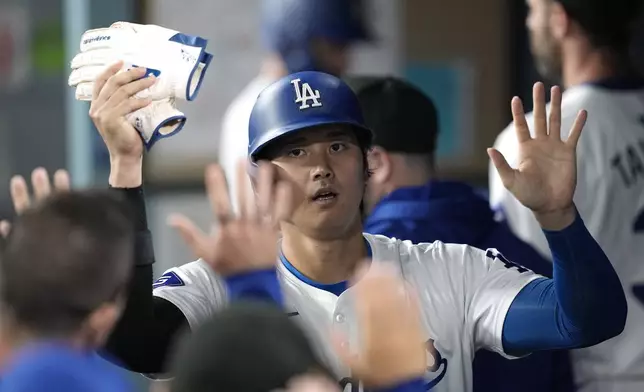 Los Angeles Dodgers' Shohei Ohtani is congratulated by teammates in the dugout after scoring on a single by Will Smith during the seventh inning of a baseball game Friday, May 17, 2024, in Los Angeles. (AP Photo/Mark J. Terrill)