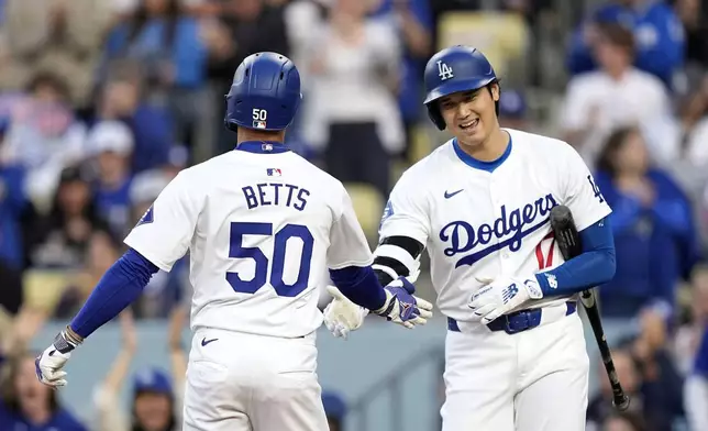 Los Angeles Dodgers' Mookie Betts, left, is congratulated by Shohei Ohtani after hitting a solo home run during the first inning of a baseball game against the Cincinnati Reds Friday, May 17, 2024, in Los Angeles. (AP Photo/Mark J. Terrill)