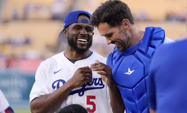 Former NFL and University of Southern California running back Reggie Bush, left, jokes with former USC quarterback Matt Leinart after throwing out the ceremonial first pitch prior to a baseball game between the Los Angeles Dodgers and the Cincinnati Reds Friday, May 17, 2024, in Los Angeles. (AP Photo/Mark J. Terrill)