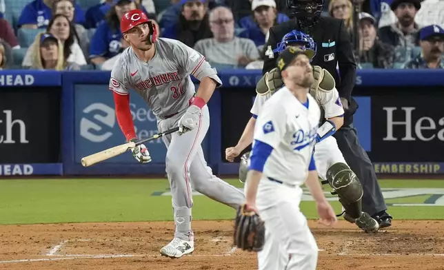 Cincinnati Reds' Tyler Stephenson, left, heads to first after hitting a solo home run as Los Angeles Dodgers hitting coach Aaron Bates, right, watches during the sixth inning of a baseball game Friday, May 17, 2024, in Los Angeles. (AP Photo/Mark J. Terrill)