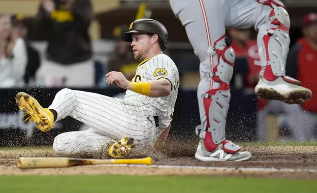 San Diego Padres' Jake Cronenworth, left, slides in to score off a three-RBI double during the fifth inning of a baseball game against the Cincinnati Reds, Tuesday, April 30, 2024, in San Diego. (AP Photo/Gregory Bull)