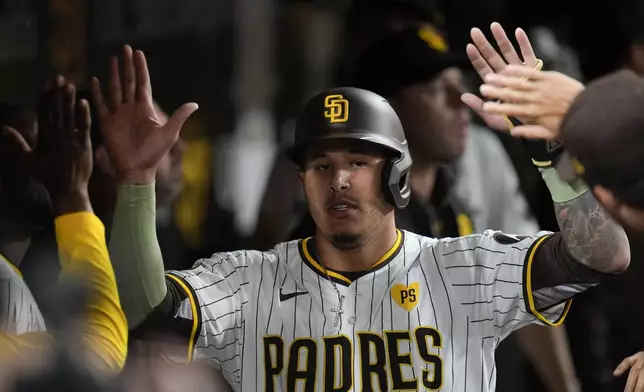 San Diego Padres' Manny Machado is greeted in the dugout after scoring from second base off a fielding error by Cincinnati Reds left fielder Spencer Steer during the fifth inning of a baseball game, Tuesday, April 30, 2024, in San Diego. (AP Photo/Gregory Bull)