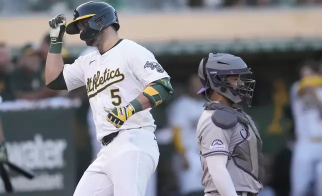 Oakland Athletics' J.D. Davis (5) reacts after hitting a home run next to Colorado Rockies catcher Elias Díaz during the third inning of a baseball game in Oakland, Calif., Tuesday, May 21, 2024. (AP Photo/Jeff Chiu)
