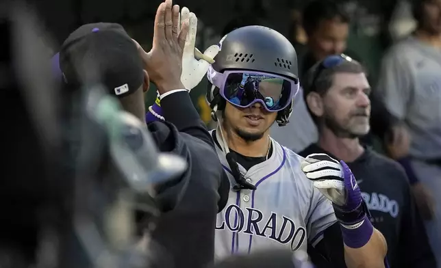Colorado Rockies' Ezequiel Tovar, middle, is congratulated by teammates after hitting a home run during the seventh inning of a baseball game against the Oakland Athletics in Oakland, Calif., Tuesday, May 21, 2024. (AP Photo/Jeff Chiu)