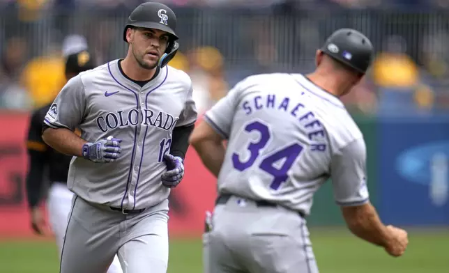 Colorado Rockies' Sean Bouchard (12) rounds third to greetings from third base coach/infield coach Warren Schaeffer (34) after hitting a solo home run off Pittsburgh Pirates starting pitcher Bailey Falter during the second inning of a baseball game in Pittsburgh, Sunday, May 5, 2024. (AP Photo/Gene J. Puskar)