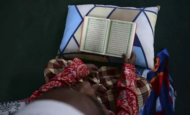 Bashir Ahmed, a Rohingya survivor of a capsized refugee boat, reads the Quran at his temporary shelter in Meulaboh, Indonesia, on Thursday, April 4, 2024. Bashir was among 75 people rescued from atop the overturned hull of the boat, which capsized off Indonesia's coast in March. Dozens of others died. (AP Photo/Reza Saifullah)