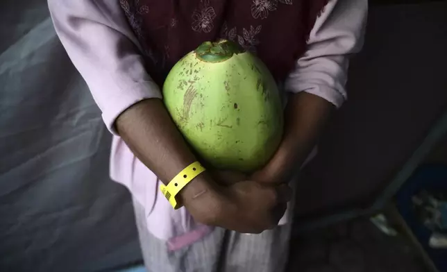 N, a 12-year-old ethnic Rohingya refugee identified by The Associated Press with only an initial, because she is a sexual assault survivor, holds a coconut ahead of breaking her Ramadan fast at a temporary shelter in Meulaboh, Indonesia, on Wednesday, April 3, 2024. N was forced to leave behind her family when she fled Bangladesh on a boat packed with other Rohingya refugees. She hoped to make it to Malaysia, where she'd been promised as a child bride to a man she'd never met. (AP Photo/Reza Saifullah)