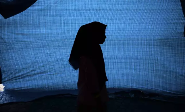 N, a 12-year-old ethnic Rohingya refugee identified by The Associated Press with only an initial, because she is a sexual assault survivor, stands in her tent at a temporary shelter in Meulaboh, Indonesia, on Thursday, April 4, 2024. N was among 75 people rescued from atop an overturned fishing boat off the Indonesian coast in March. Dozens of other Rohingya refugees died. (AP Photo/Reza Saifullah)