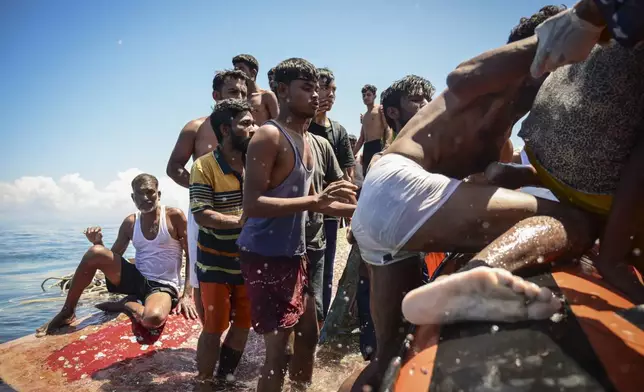 Ethnic Rohingya refugees climb onto a National Search and Rescue Agency boat after their boat capsized off West Aceh, Indonesia, on Thursday, March 21, 2024. The wooden fishing boat carried about 140 Rohingya refugees, but only 75 people were rescued. In interviews with The Associated Press, eight of the survivors described abuses on board the fishing boat. (AP Photo/Reza Saifullah)