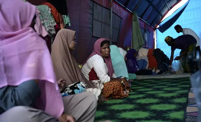 Rahena Begum, third from left, a survivor of a capsized refugee boat, sits with other ethnic Rohingya women at their temporary shelter in Meulaboh, Indonesia, on Thursday, April 4, 2024. In March, Indonesian officials and local fishermen rescued 75 people from atop the overturned hull of the boat. Dozens of other Rohingya refugees died. (AP Photo/Reza Saifullah)