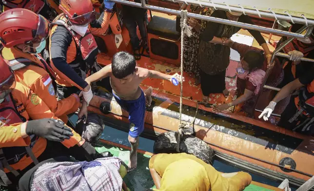 Ethnic Rohingya refugees board a National Search and Rescue Agency ship after being rescued from their capsized boat in the waters off West Aceh, Indonesia, on Thursday, March 21, 2024. The wooden fishing boat carried about 140 Rohingya refugees, but only 75 people were rescued. In interviews with The Associated Press, eight of the survivors described abuses on board the fishing boat. (AP Photo/Reza Saifullah)