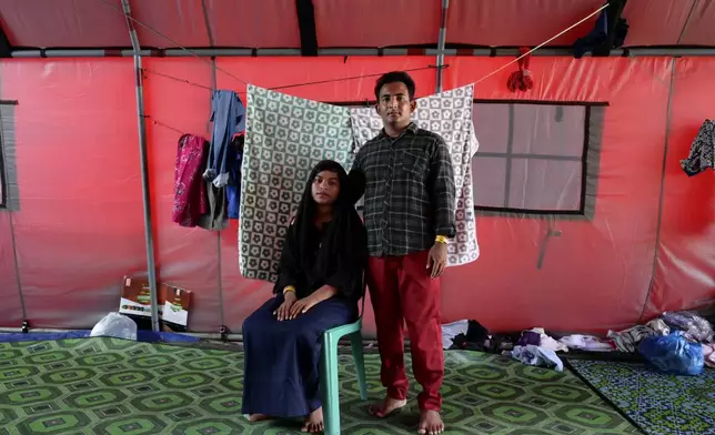 Samira, left, and her husband, Akram Ullah, both ethnic Rohingya refugees, pose for a photograph at a temporary shelter in Meulaboh, Indonesia, on Thursday, April 4, 2024. They were among 75 people rescued in March from atop the overturned hull of a boat that capsized off Indonesia's coast. Dozens of other Rohingya refugees died. (AP Photo/Reza Saifullah)
