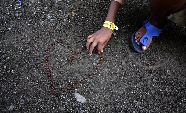 Umar Faruq, a 9-year-old ethnic Rohingya refugee who survived a boat capsize, arranges tamarind seeds in the shape of a heart at a temporary shelter in Meulaboh, Indonesia, on Wednesday, April 3, 2024. Umar was among 75 people rescued in March from atop the overturned hull of the boat, which capsized off Indonesia's coast. Dozens of other Rohingya refugees, including at least 28 children, died. (AP Photo/Reza Saifullah)