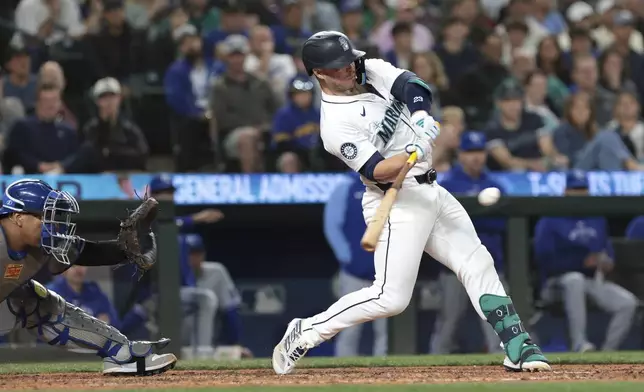 Seattle Mariners' Ty France hits a single next to Kansas City Royals catcher Salvador Perez during the eighth inning of a baseball game Tuesday, May 14, 2024, in Seattle. (AP Photo/Jason Redmond)