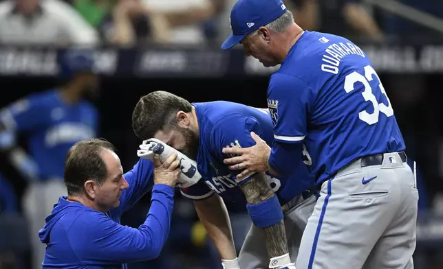 Kansas City Royals' Kyle Isbel, center, is helped by manager Matt Quatraro (33) and a trainer after fouling a pitch off of his face during the seventh inning of a baseball game against the Tampa Bay Rays, Saturday, May 25, 2024, in St. Petersburg, Fla. (AP Photo/Phelan M. Ebenhack)