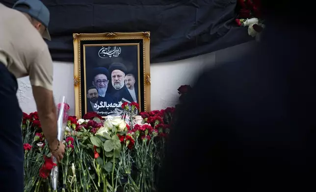 A man lays flowers near a photo of Iranian President Ebrahim Raisi and his colleagues at a makeshift memorial at the Iranian Embassy in Moscow, Russia, Monday, May 20, 2024. Raisi, a hard-line protege of the country's supreme leader who helped oversee the mass executions of thousands in 1988 and later led the country as it enriched uranium near weapons-grade levels, launched a major attack on Israel and experienced mass protests, has died Sunday, May 19. (AP Photo/Alexander Zemlianichenko)