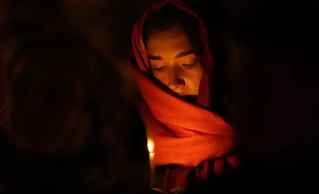 An Orthodox believer looks at her candle during Orthodox Easter midnight service at a church in St. Petersburg, Russia, Sunday, May 5, 2024. Eastern Orthodox churches observe the ancient Julian calendar and this year celebrate Orthodox Easter on May 5. (AP Photo/Dmitri Lovetsky)