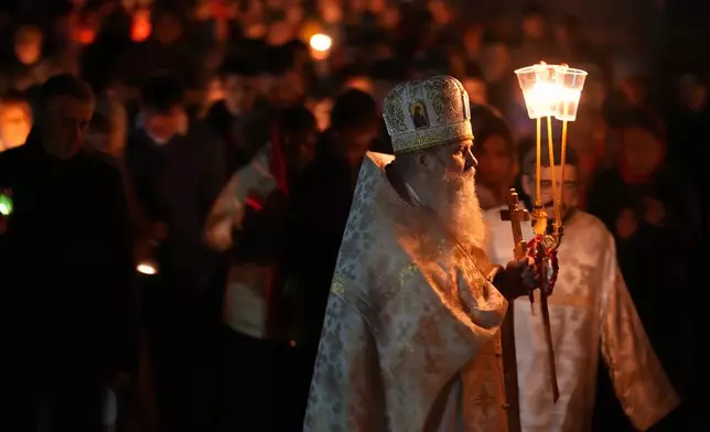Orthodox pries and believers walk with candles around a church during Orthodox Easter midnight service in St. Petersburg, Russia, Sunday, May 5, 2024. Eastern Orthodox churches observe the ancient Julian calendar and this year celebrate Orthodox Easter on May 5. (AP Photo/Dmitri Lovetsky)