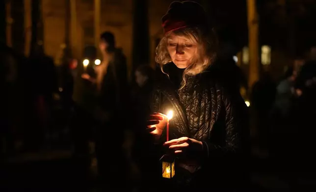 An Orthodox believer puts out her candle after Orthodox Easter midnight service at a church in St. Petersburg, Russia, Sunday, May 5, 2024. Eastern Orthodox churches observe the ancient Julian calendar and this year celebrate Orthodox Easter on May 5. (AP Photo/Dmitri Lovetsky)