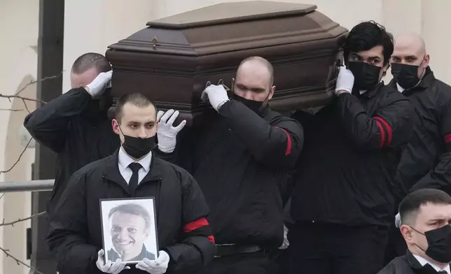 FILE - Workers carry the coffin and a portrait of Russian opposition leader Alexei Navalny in Moscow, Russia, Friday, March 1, 2024. Navalny, President Vladimir Putin's greatest political foe, died in an Arctic penal colony in February. Other prominent critics have either been imprisoned or have fled the country. (AP Photo, File)