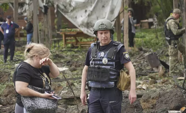 A woman cries as police officers inspect the site of the Russian missile attack that hit a recreation area killing five including one pregnant, injuring 16 in the outskirts of Kharkiv, Ukraine, Sunday, May 19, 2024. (AP Photo/Andrii Marienko)