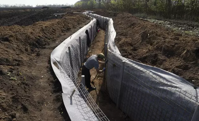 A worker constructs new defensive positions close to the Russian border in Kharkiv region, Ukraine, on Wednesday, April 17, 2024. (AP Photo/Evgeniy Maloletka)