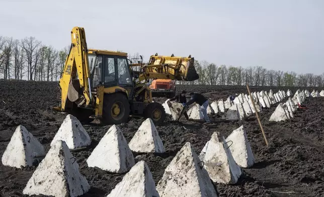 Workers install anti-tank systems known as “dragon teeth” during construction new defensive positions close to the Russian border in Kharkiv region, Ukraine, on Wednesday, April 17, 2024. (AP Photo/Evgeniy Maloletka)