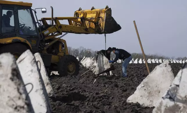 Workers install anti-tank defenses known as “dragon teeth” during construction of new defensive positions close to the Russian border in the Kharkiv region, Ukraine, on Wednesday, April 17, 2024. (AP Photo/Evgeniy Maloletka)