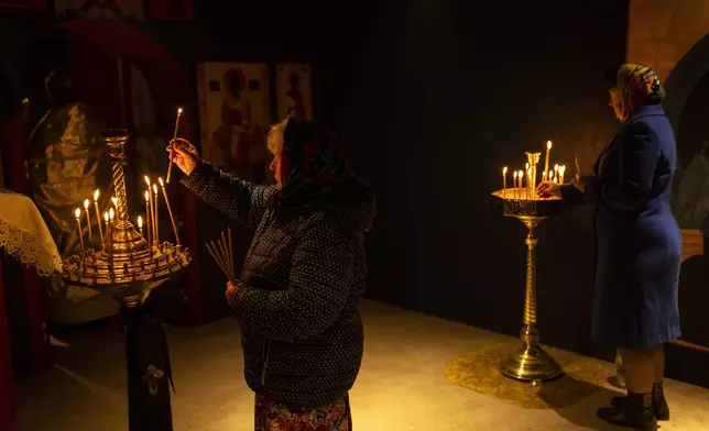 Orthodox Christian worshippers light candles during a ceremony at the Church of the Intercession in Lypivka, near Kyiv, Ukraine, Sunday, April 28, 2024. (AP Photo/Francisco Seco)