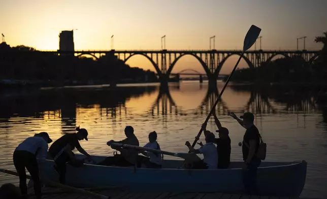Ukrainians, a few of them displaced from Mariupol during the war, train at rowing on the Dnipro river as the sun sets, in Dnipro, Ukraine, Thursday, May 2, 2024. (AP Photo/Francisco Seco)