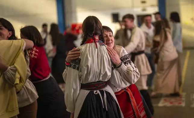 Women wearing traditional Ukrainian costumes greet and dance with others in a market in Kyiv, Ukraine, Sunday, April 28, 2024. (AP Photo/Francisco Seco)
