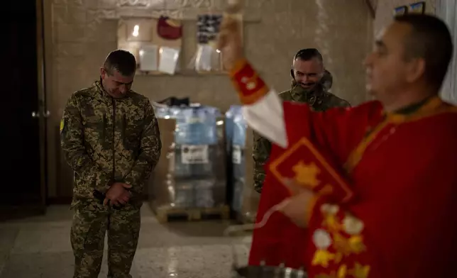 Priest Ivan, blesses Ukrainian servicemen of the 72nd Separate Mechanized Brigade, during a Christian Orthodox Easter religious service Donetsk region, Ukraine, early Sunday, May 5, 2024. (AP Photo/Francisco Seco)