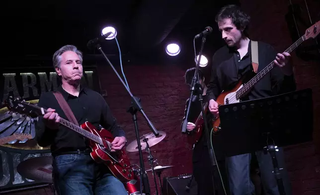 US Secretary of State Antony Blinken, left, performs "Rockin' in the Free World" with members of The 1999 band at the Barman Dictat bar in Kyiv, Tuesday, May 14, 2024. Blinken sought Tuesday to rally the spirits of glum Ukrainians facing a fierce new Russian offensive, assuring them that they are not alone and that billions of dollars in American military aid on its way to the country would make a “real difference” on the battlefield. (Brendan Smialowski/Pool photo via AP)