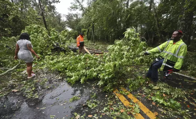 Residents of an apartment complex try to clear Old St. Augustine Road of trees and debris in Tallahassee, Fla., Friday, May 10, 2024. Powerful storms with damaging high winds threatened several states in the Southeast early Friday. (AP Photo/Phil Sears)