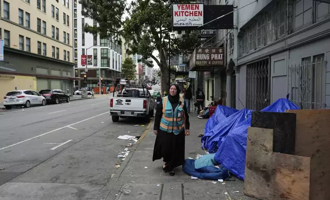 Tatiana Alabsi walks past a small encampment as she roams the Tenderloin neighborhood before children walk to school Wednesday, April 24, 2024, in San Francisco. (AP Photo/Godofredo A. Vásquez)