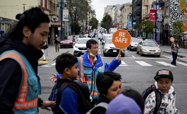 Hung Truong, background, with Safe Passage makes sure children make it safely to the Boys &amp; Girls Clubs of San Francisco for after-school programs Wednesday, March 27, 2024, in San Francisco. (AP Photo/Godofredo A. Vásquez)