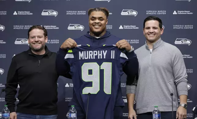 Seattle Seahawks 2024 first round draft pick, Byron Murphy II, is introduced by general manager John Schneider, left, and head coach Mike Macdonald, right, during a news conference at the NFL team's headquarters, Thursday, May 2, 2024, in Renton, Wash. (AP Photo/ John Froschauer)