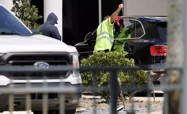 Workers attempt to gain access to a Bentley SUV in the driveway at Sean Kingston's Southwest Ranches, Fla., home on Thursday, May 23, 2024. A SWAT team raided rapper Kingston's rented mansion on Thursday, and arrested his mother on fraud and theft charges that an attorney says stems partly from the installation of a massive TV at the home. Broward County detectives arrested Janice Turner, 61, at the home. (Amy Beth Bennett/South Florida Sun-Sentinel via AP)