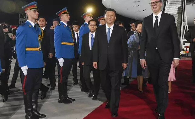 In this image provided by the Serbian Presidential Press Service, Chinese President Xi Jinping, center, reviews the honor guard with his Serbian counterpart Aleksandar Vucic during a welcome ceremony upon his arrival at the Nikola Tesla airport in Belgrade, Serbia, Tuesday, May 7, 2024. (Serbian Presidential Press Service via AP)