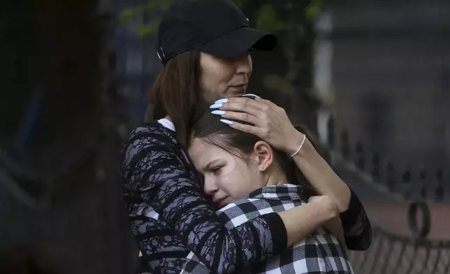 FILE - A woman hugs a girl near the Vladislav Ribnikar school in Belgrade, Serbia, Wednesday, May 3, 2023. A teenage boy opened fire at the school on the morning of May 3, 2023. Eight children and a school guard died, and seven people were wounded. One of the wounded, a child, died from injuries later. A total of 10 people were killed. (AP Photo/Armin Durgut, File)