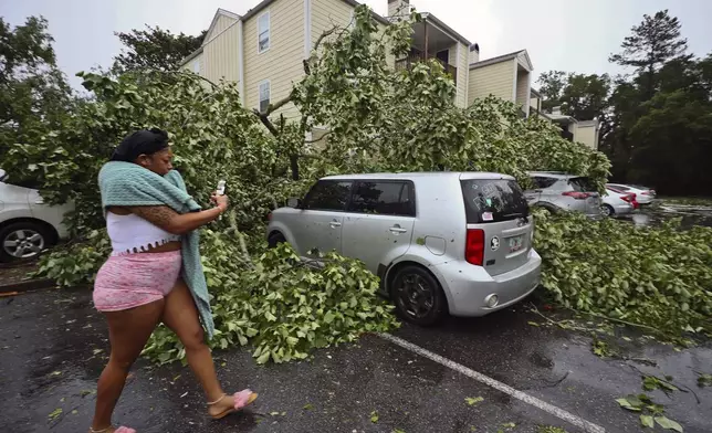 A resident records the damage to cars outside an apartment complex in Tallahassee, Fla., Friday, May 10, 2024. Powerful storms bringing the threat of tornadoes continued to slam several southern states early Friday, as residents cleared debris from deadly severe weather that produced twisters in Michigan, Tennessee and other states. Some of the strongest storms early Friday rolled into Tallahassee (AP Photo/Phil Sears)