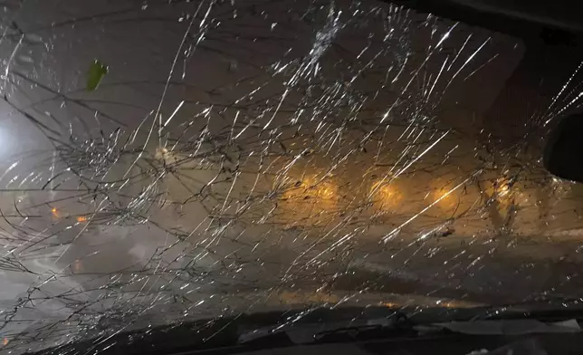 This image provided by JJ Unger, shows hail damage to the window of vehicle, Monday night, May 20, 2024, in Yuma, Colo. Residents in the small city in northeastern Colorado were cleaning up Tuesday after hail the size of baseballs and golf balls pounded the community, with heavy construction equipment and snow shovels being used to clear hail that had piled up knee-deep the night before. (JJ Unger via AP)