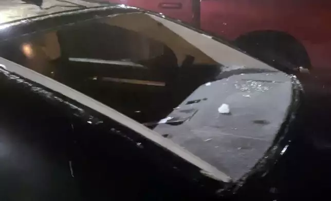 This image taken from video provided by JJ Unger, shows hail damage to a window of vehicle, Monday night, May 20, 2024, in Yuma, Colo. Residents in the small city in northeastern Colorado were cleaning up Tuesday after hail the size of baseballs and golf balls pounded the community, with heavy construction equipment and snow shovels being used to clear hail that had piled up knee-deep the night before. (JJ Unger via AP)