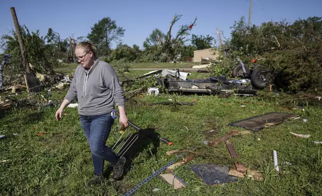 A woman walks around debris and damage caused by powerful storms, Tuesday, May 7, 2024 in Barnsdall, Okla. (Mike Simons/Tulsa World via AP)