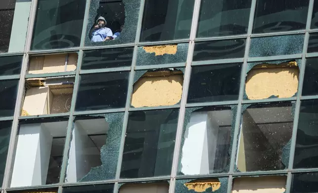FILE - Workers clean out shattered glass at the Wells Fargo building as clean up from the previous week's storm continues in downtown Houston, Monday, May 20, 2024. (Brett Coomer/Houston Chronicle via AP, file)